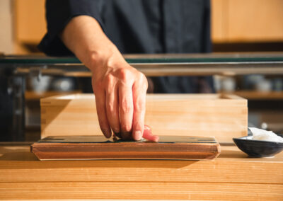 Sushi chef serving a piece of nigiri at the counter of Sushi Shutatsu in Ogikubo, Tokyo