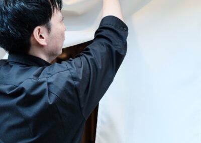 Staff adjusting the entrance noren curtain at Sushi Shutatsu in Ogikubo.