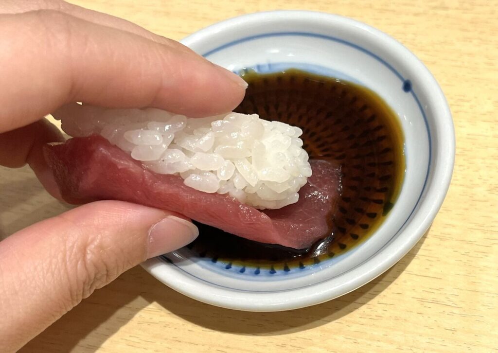 Proper way to dip sushi into soy sauce by touching only the fish side, not the rice