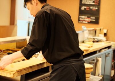 Sushi chef preparing ingredients behind the counter at Sushi Shutatsu in Ogikubo, Tokyo.