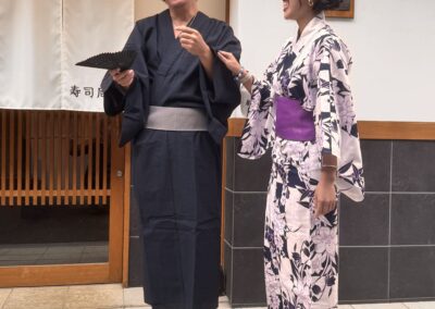 Guests wearing traditional yukata smiling and chatting in front of Sushi Shutatsu in Ogikubo.