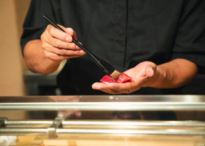 Sushi chef brushing nikiri sauce on a piece of tuna nigiri at Sushi Shutatsu in Tokyo