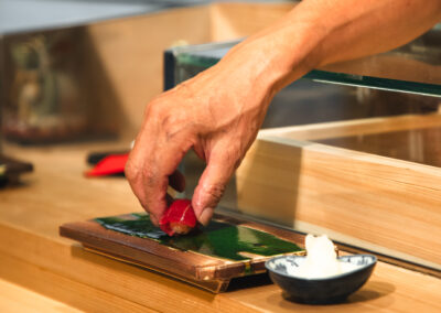 Chef placing a piece of tuna sushi onto a wooden sushi geta at Sushi Shutatsu.