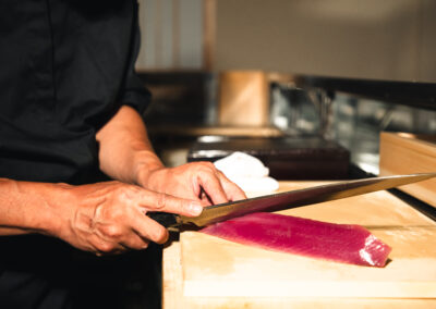 Chef slicing fresh tuna with a long sushi knife at Sushi Shutatsu in Ogikubo.