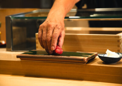 Sushi chef placing a piece of tuna nigiri on a wooden board at Sushi Shutatsu in Tokyo